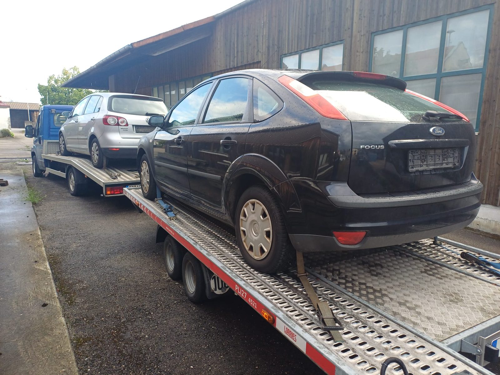 Altauto-Abholung im Raum Ulm: schwarzer Ford Focus ohne Kennzeichen verzurrt auf dem Anhänger, davor der bereits beladene Transporter